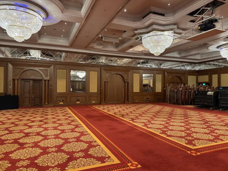 Spacious banquet hall with chandeliers and red carpet flooring